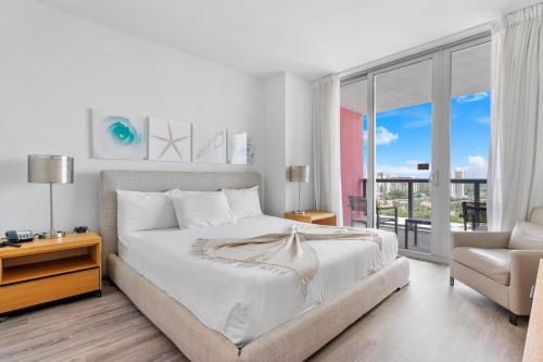 ein weißes Schlafzimmer mit einem großen Bett und einem Stuhl in der Unterkunft Modern two bed Beach Walk Miami 15th in Hollywood