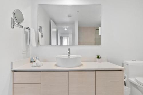 a white bathroom with a sink and a mirror at Modern one bedroom rental at Beach Walk Resort 17th floor Miami in Hollywood