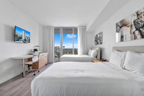a hotel room with two beds and a desk and a window at Studio at Beach Walk resort 17th floor Miami in Hollywood