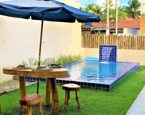 a table with an umbrella next to a swimming pool at Casa Conchas do Patacho in Pôrto de Pedras
