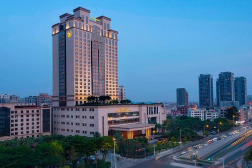 un edificio alto con un reloj en una ciudad en Sheraton Dongguan Hotel en Dongguan