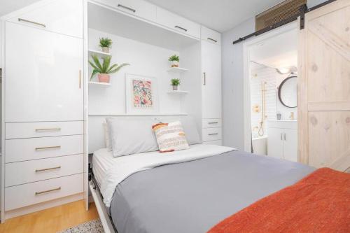 ein weißes Schlafzimmer mit einem Bett und einem Schrank in der Unterkunft Charming 1BD Townhouse Near Lake in Toronto
