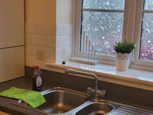 um lavatório de cozinha com uma toalha verde e uma janela em The Haven Comfort em Harold Wood
