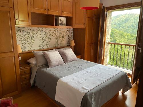 ein Schlafzimmer mit einem Bett und einem großen Fenster in der Unterkunft La Xana del Profundu in Villaviciosa