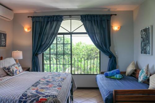 a bedroom with two beds and a large window at Casa Mimosa in Playa Flamingo