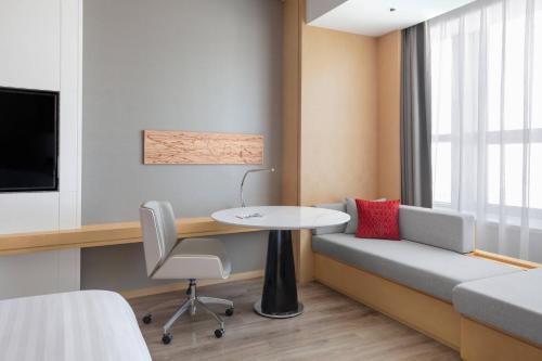 a room with a couch and a table and a bed at Courtyard by Marriott Shanghai Songjiang in Songjiang