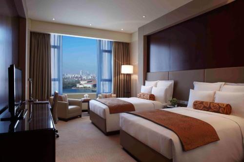 a hotel room with two beds and a large window at Renaissance Tianjin Lakeview Hotel in Tianjin