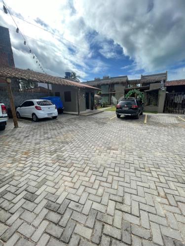 un parcheggio con due auto parcheggiate di fronte a un edificio di Nauru chalés milagres a São Miguel dos Milagres