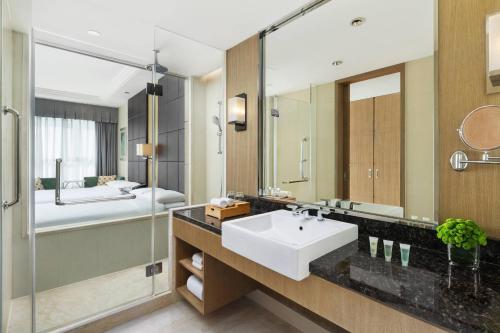 a bathroom with a sink and a bed and a mirror at Courtyard by Marriott Kunshan in Kunshan