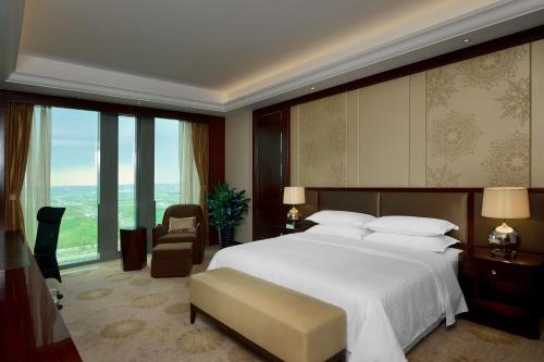 a bedroom with a large bed and a large window at Sheraton Shenyang South City Hotel in Shenyang