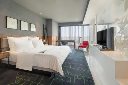 um quarto de hotel com uma cama e uma televisão de ecrã plano em Le Meridien Zhengzhou em Zhengzhou