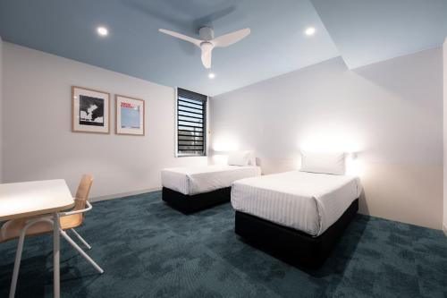 een kamer met 2 bedden, een bureau en een tafel bij The Lodge, Blacktown - Sydney in Rooty Hill