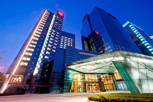 a large glass building in front of tall buildings at Sheraton Grand Beijing Dongcheng Hotel in Beijing