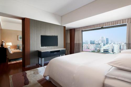 Habitación de hotel con cama grande y ventana grande. en Sheraton Grand Beijing Dongcheng Hotel, en Beijing