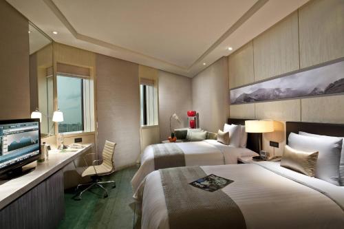 a hotel room with two beds and a television at Courtyard By Marriott Shanghai Pudong in Shanghai