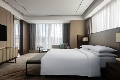 a bedroom with a large white bed and a television at Hangzhou Marriott Hotel Lin'an in Lin'an