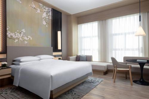 una camera con letto bianco, tavolo e scrivania di Courtyard by Marriott Jiangsu Taizhou a Taizhou