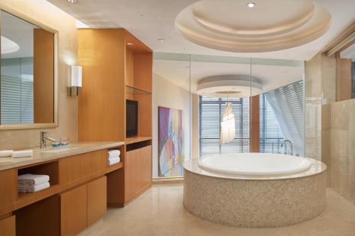 a bathroom with a tub and a large mirror at Sheraton Yantai Golden Beach Resort in Yantai