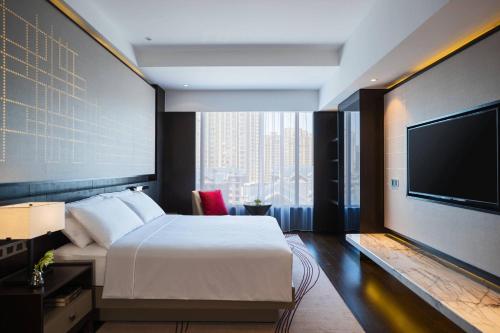 a hotel room with a bed and a flat screen tv at Renaissance Shenyang West Hotel in Shenyang