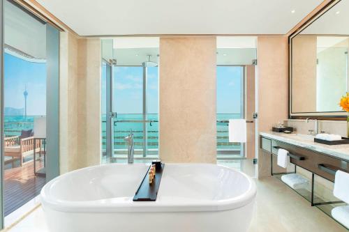 a large white tub in a bathroom with a balcony at Sheraton Zhuhai Hotel in Zhuhai