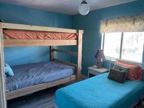 a bedroom with two bunk beds and a blue wall at Wanderlust Villa only 3 min walk to the Sand! in Panama City Beach