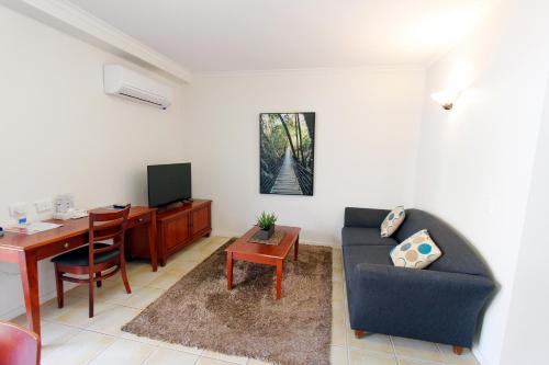 a living room with a desk and a couch and a table at Coffee House Apartment Motel in Rockhampton