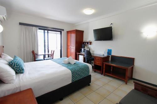 a bedroom with a bed and a desk with a computer at Coffee House Apartment Motel in Rockhampton