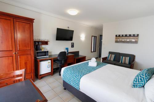 a hotel room with a bed and a desk and a television at Coffee House Apartment Motel in Rockhampton