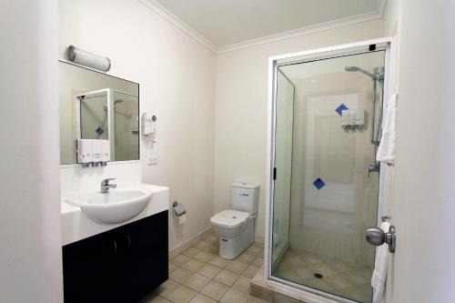 a bathroom with a shower and a sink and a toilet at Coffee House Apartment Motel in Rockhampton