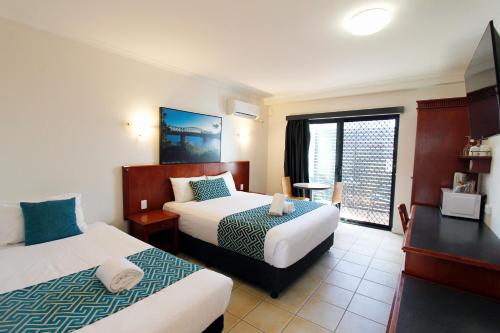 a hotel room with two beds and a balcony at Coffee House Apartment Motel in Rockhampton