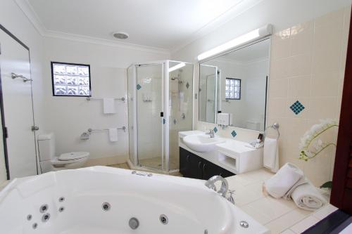 a bathroom with a tub and two sinks and a shower at Coffee House Apartment Motel in Rockhampton