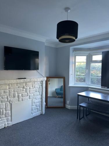 a living room with a stone fireplace and a tv at Kenton Apartment- Wembley links in Harrow Weald