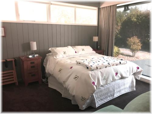 a bedroom with a bed with a white comforter and a window at Peaceful Pukerua Bay in Pukerua Bay