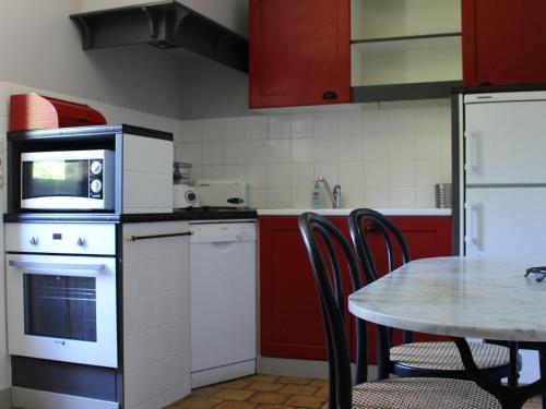 una cocina con armarios rojos y una mesa con sillas. en Gîte Berfay, 3 pièces, 6 personnes - FR-1-410-242, en Berfay