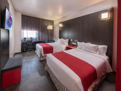 a hotel room with two beds and a desk at Ramada Encore by Wyndham Aguascalientes in Aguascalientes