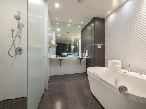 ein weißes Badezimmer mit einer Badewanne und einem Waschbecken in der Unterkunft Ramada Encore by Wyndham Aguascalientes in Aguascalientes