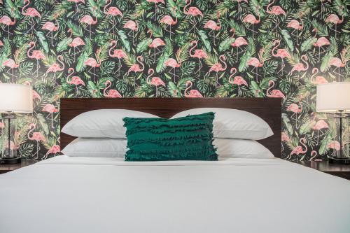 a bed with a green pillow in front of a floral wallpaper at The Local - St. Augustine in Saint Augustine
