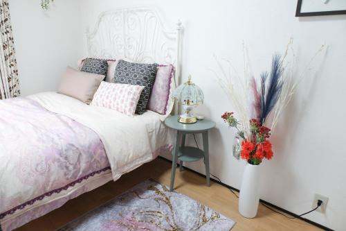 a bedroom with a bed and a table with a vase of flowers at Housegreen201 in Tokyo