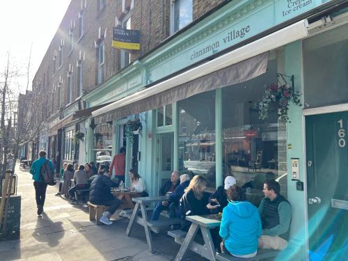 a group of people sitting at tables outside of a store at Islington Apartments in London
