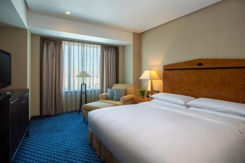 a hotel room with a large bed and a chair at Renaissance Tianjin TEDA Convention Centre Hotel in Binhai