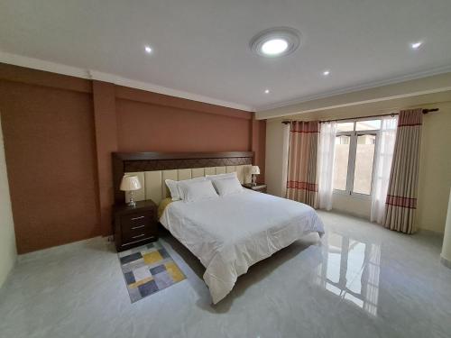 Un dormitorio con una gran cama blanca y una ventana en Apartamento amplio, cómodo y desestresante!!! en Cochabamba