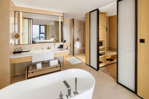 a bathroom with a tub and a sink and a mirror at Suining Marriott Hotel in Suining