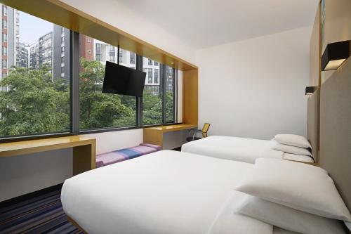 a hotel room with two beds and a flat screen tv at Aloft Guangzhou University Park in Guangzhou