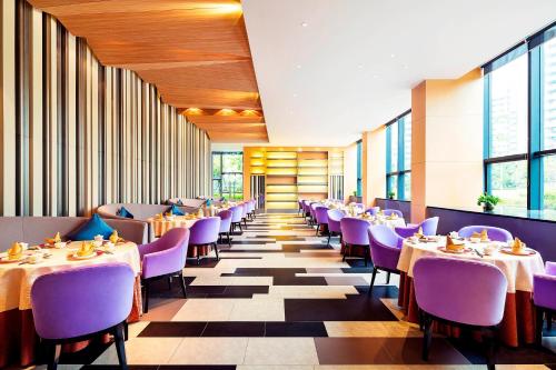 a dining room with tables and purple chairs at Aloft Guangzhou University Park in Guangzhou