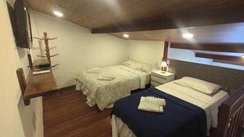 a small room with two beds and a tv at Solar Flats - WooD - Pipa RN in Pipa