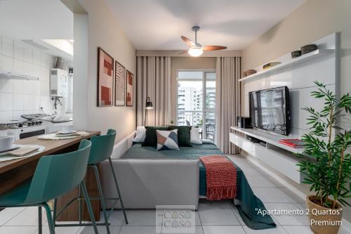 a kitchen and a living room with a couch and a table at 2 QUARTOS a 200m RIOCENTRO em CONDOMINIO com PISCINA, Estacionamento e Portaria 24h - Area de LAZER tambem para CRIANCAS - Wi-Fi 120mbps e Cozinha Completa in Rio de Janeiro