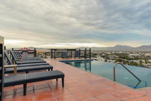 a swimming pool with lounge chairs on top of a building at Morgan Hotel Boutique & Residences, Los Cabos in Cabo San Lucas