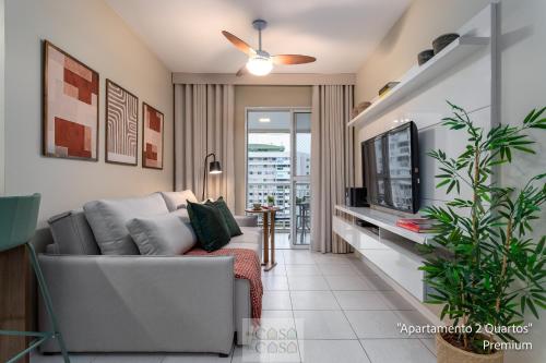ein Wohnzimmer mit Couch und Fernseher in der Unterkunft 2 Quartos com Varanda a 300m RioCentro Wi-Fi 120mbps e Cozinha Completa - Condomínio com Piscina, Estacionamento, Portaria 24h e Parquinho Infantil - Apartamento indicado para Grupos, Hóspedes a Trabalho e Crianças in Rio de Janeiro