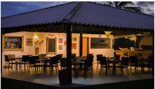 um restaurante com mesas e cadeiras debaixo de um guarda-sol em Apartamento Master VIP com 3 suítes noTree Bies Resort em Subaúma