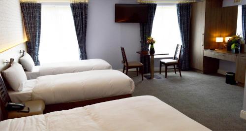a hotel room with two beds and a table and chairs at Slaney Suites in Enniscorthy